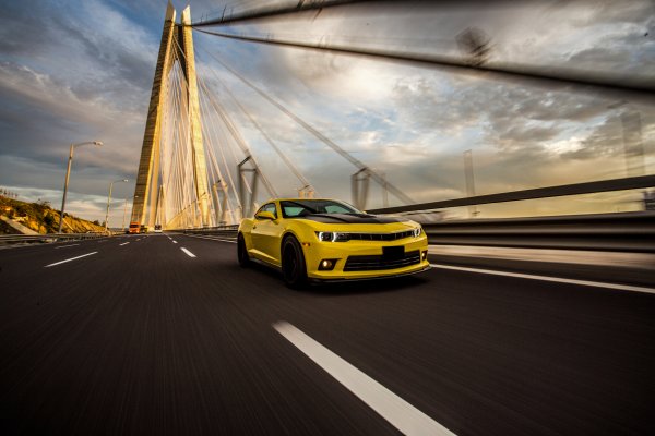Kollane tuunitud sportauto sillal – taustapilt